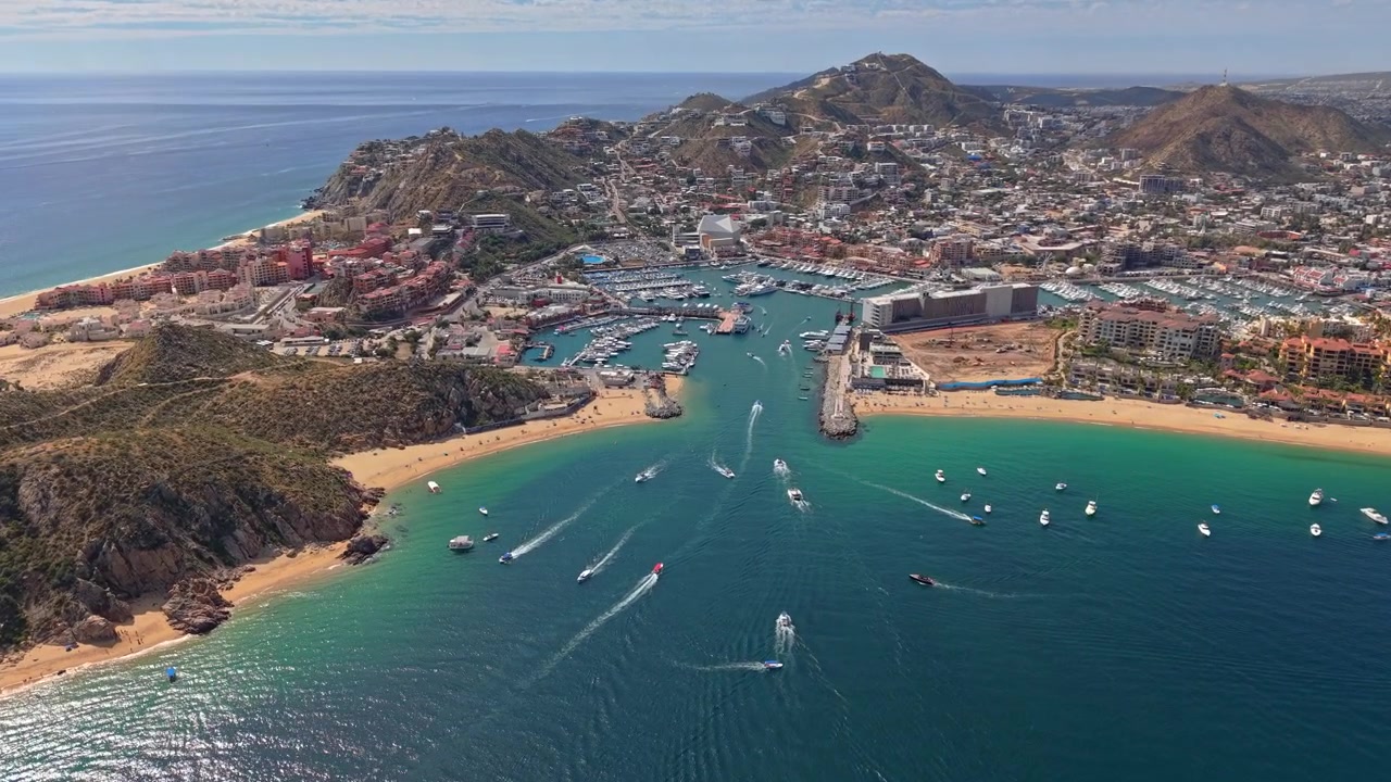 Sobrevoando Cabo San Lucas em um dia ensolarado, um destino turístico com resorts de luxo e iates, na Baja Califórnia, México.