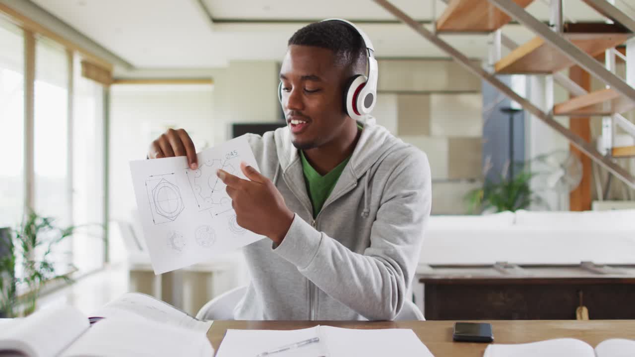 Adolescent afro-américain portant un casque audio, participant à une conversation vidéo et utilisant un ordinateur portable.