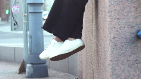 persona sentada con los pies colgando de una pared