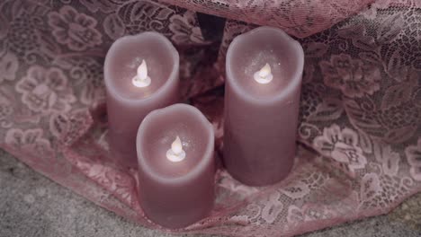 Three-LED-candles-casting-a-soft-glow-on-lace-fabric