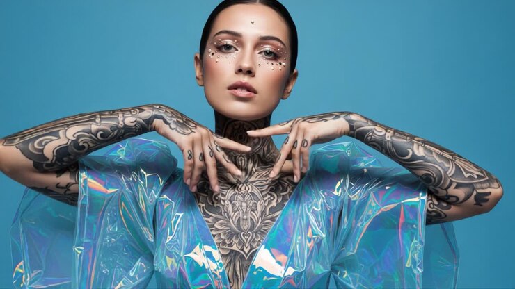 Æstetisk portræt af en model, der viser indviklede tatoveringer og blændende makeup mod en levende blå baggrund, hvilket fremhæver moderne kunstneriskhed og stil.