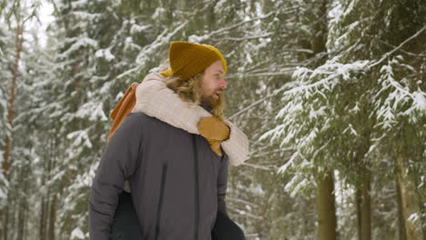 couple in winter clothes walking in winter forest