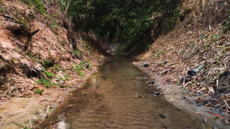 zanja de arena profunda con agua que fluye en la densa jungla vietnamita, vista hacia adelante