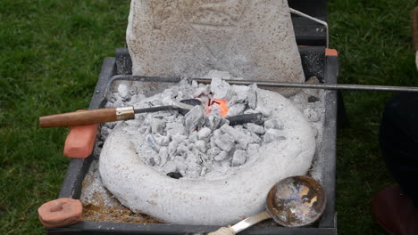 close-up of a small forge with glowing embers, blacksmith tools, and anvil, showcasing traditional metalwork