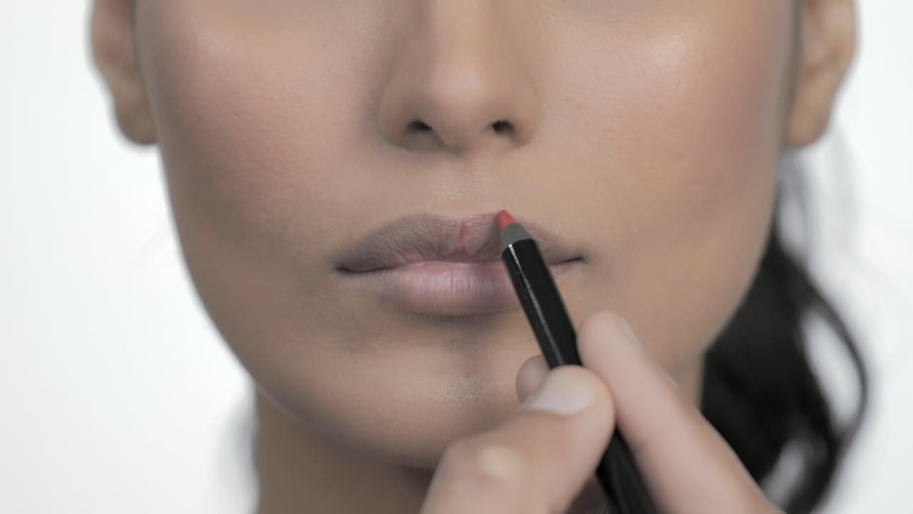maquillador aplicando lápiz labial a los labios de una mujer