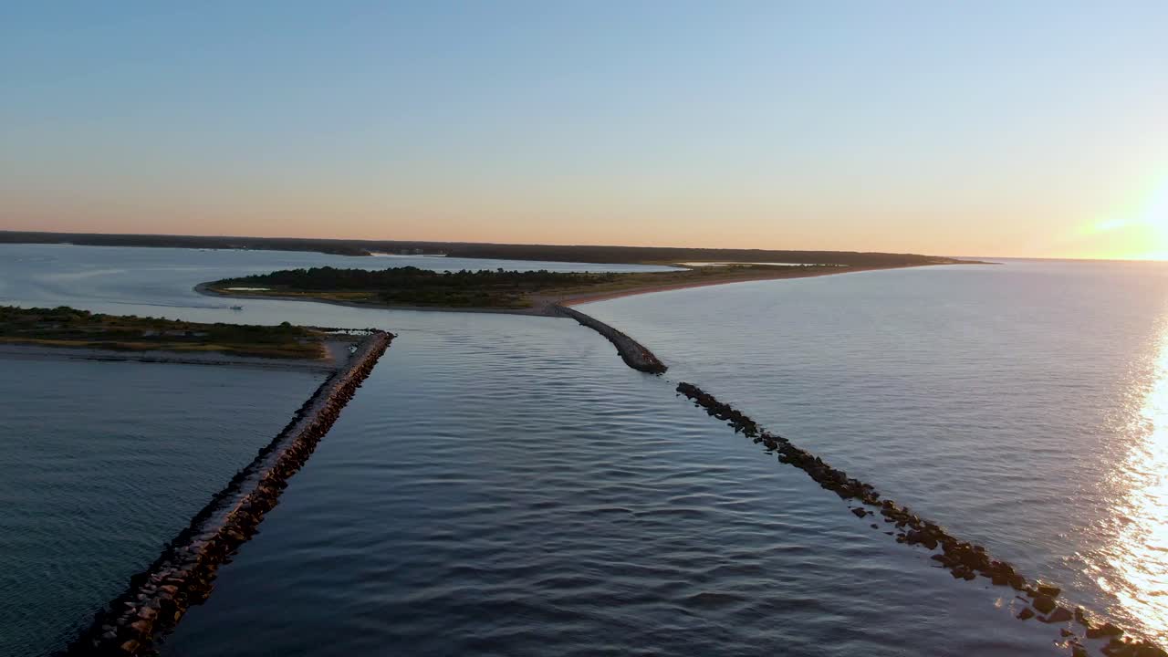 Luftfoto bagfra af strandbarrierer ved solopgang.