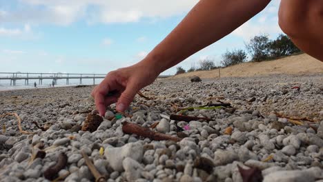 Eine-Person,-Die-Plastik-Aufsammelt,-Das-An-Einem-Beliebten-Strand-In-Der-Nähe-Einer-Stadt-Gewaschen-Wurde