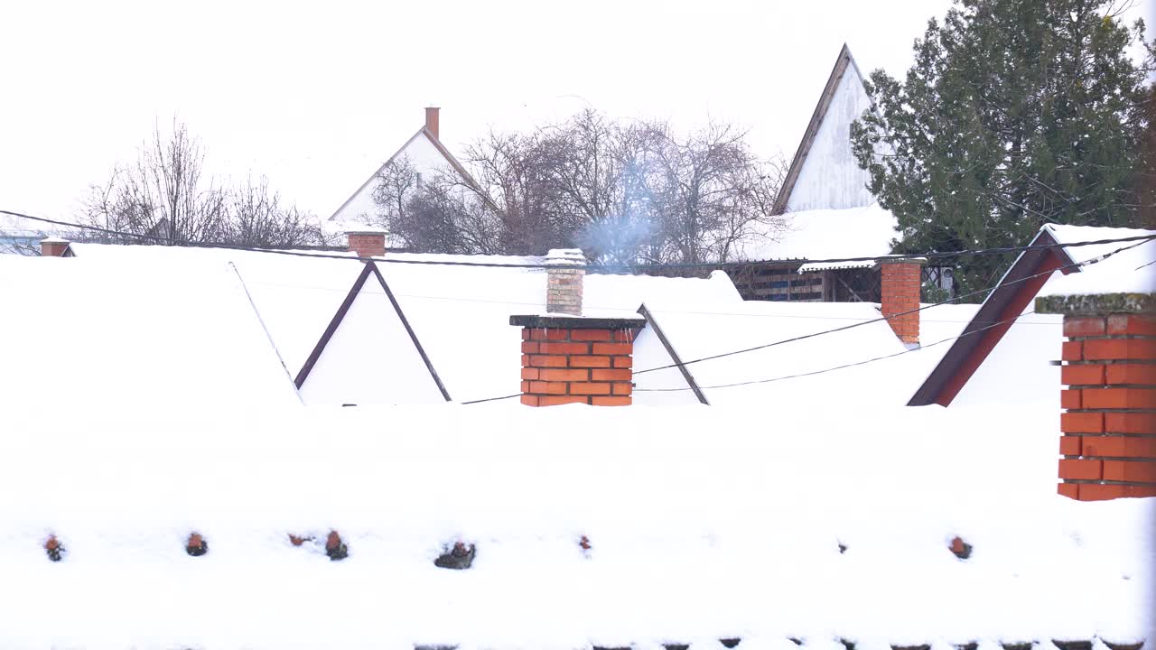 Buildings in Nemesnádudvar, Hungary, with snow-covered roofs and a chimney emitting smoke