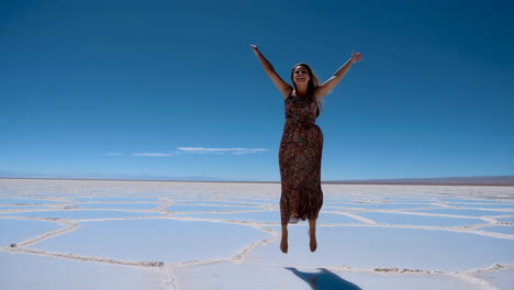 woman in dress jumps on a salt flat