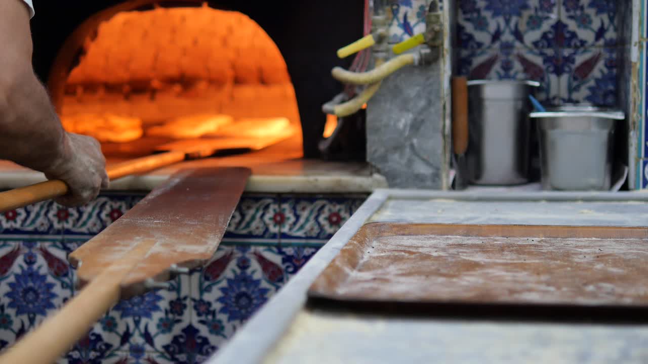 Panettiere che inforna il pane nel forno a legna