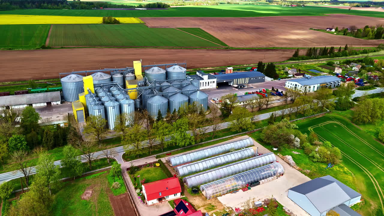 Pan drone shot of storage tanks and pipeline industry with farms at background.