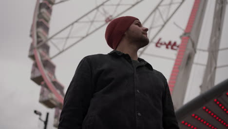 young man enters, looks around under ferris wheel in brussels belgium