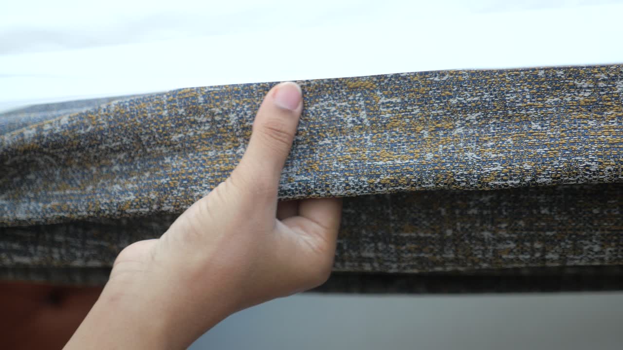 부드러운 회색과 노란색 천을 만지는 손의 근접