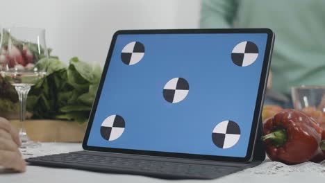 close-up of blue screen laptop with blurred senior women cooking healthful dietary food in kitchen at home. unrecognizable caucasian retirees using online recipe from web-site. cinema 4k prores hq.