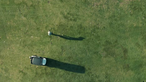 birdseye shot of a golfer with long shadows hitting a shot with an iron