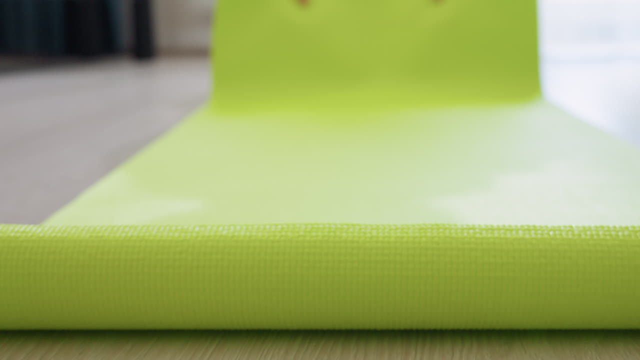 Close up of bright green fitness mat surface as someone prepares to step onto it, subtle texture and soft lighting suggest beginning of workout