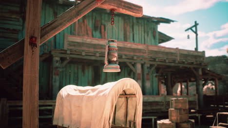 a rustic lantern hanging near a covered wagon at an old western settlement