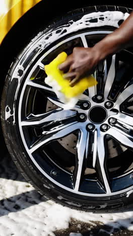 a person cleaning a car wheel with soap and a sponge