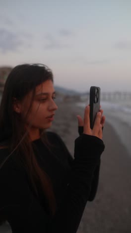 teenage girl taking photo at sunset beach