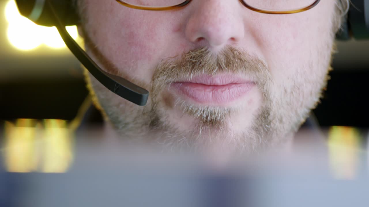 Closeup: Young bearded white male executive speaks into phone headset