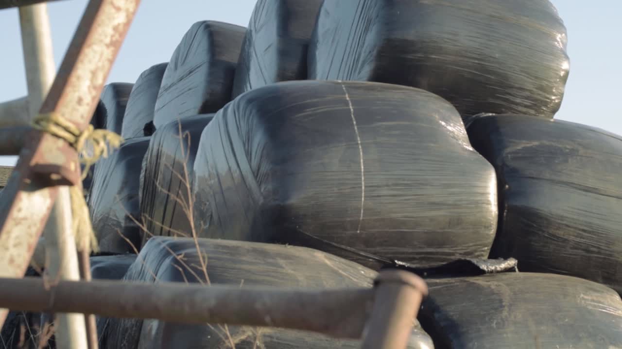 Silage bag storage in farmers field through view of gate panning shot