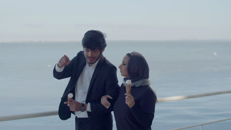 Arab-Man-And-Woman-Walking-Along-Embankment-And-Eating-Ice-Cream