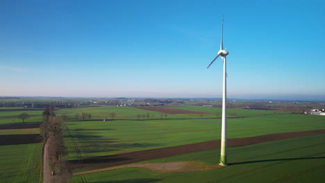 aerial orbiting shot of windmill in motion during sunny day and blue sky in rural area of poland