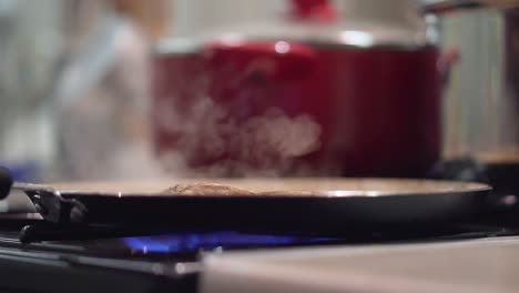 cooking meat in a pan on a gas stove