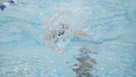 Slow-motion-shot-of-a-professional-female-swimmer,-swimming-towards-the-camera,-performing-front-crawl-during-training