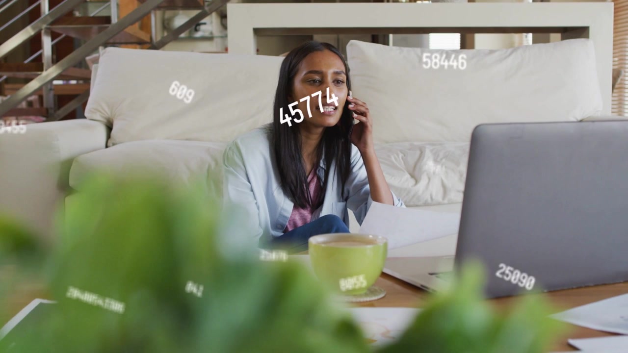 Woman taking call while scanning documents, animated data overlay highlighting business metrics
