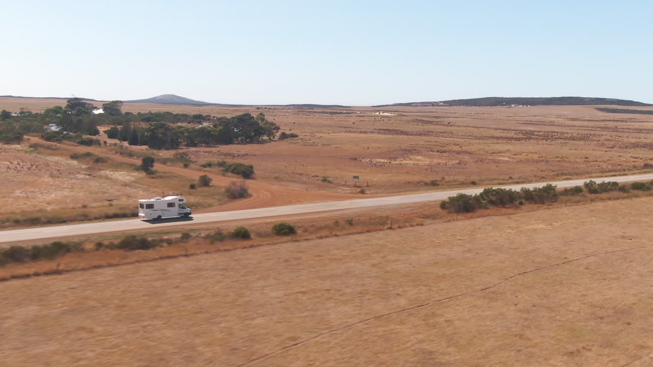 화창한 날 빈 도로에서 운전하는 캠퍼밴의 빠른 드론 접근 샷