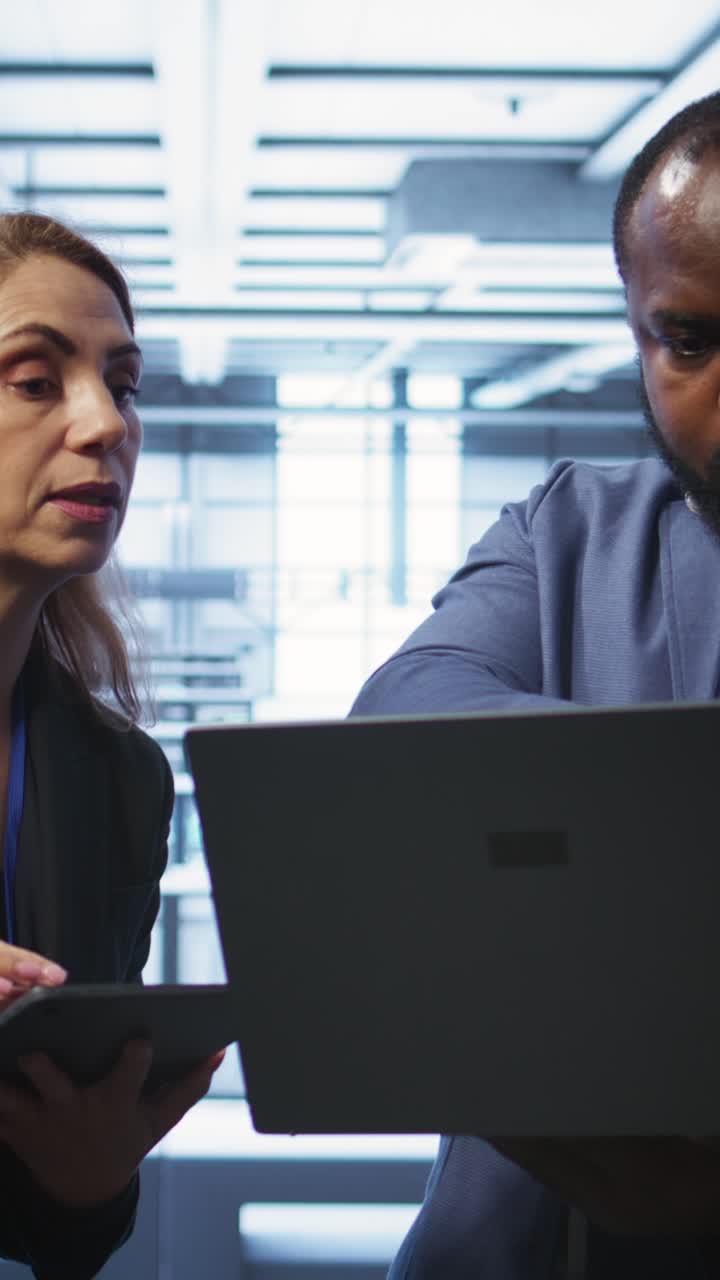 Ingegneri informatici che discutono delle operazioni della server room con laptop e tablet