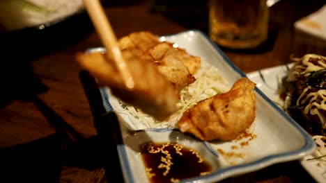 palillos para comer recogiendo gyoza de un plato de servicio