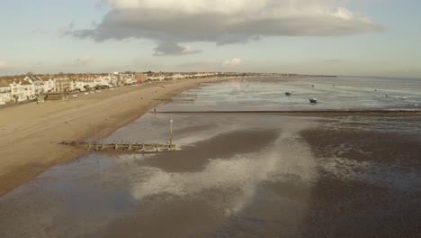 Drone-lowering-down-towards-beach-and-sand-banks-at-low-tide