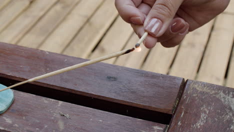 Close-up-shot-of-hand-lighting--wooden-incense-stick-with-match