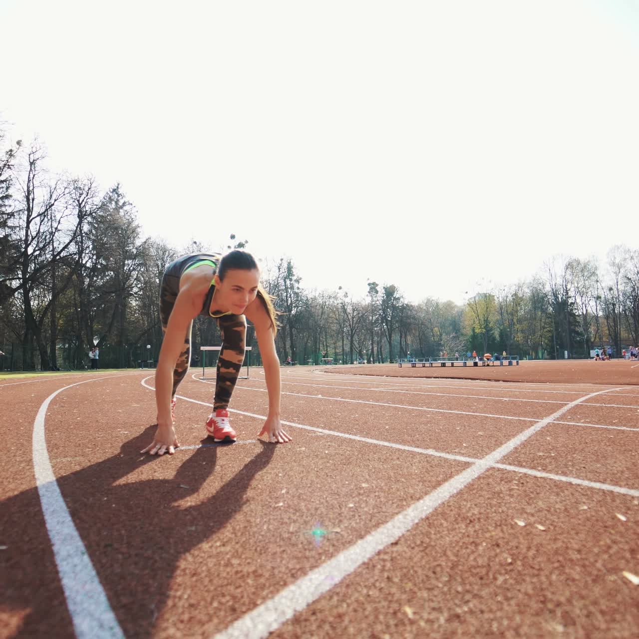 Athletic woman running on track. Track runner putting his hands at starting line. Healthy fitness lifestyle.