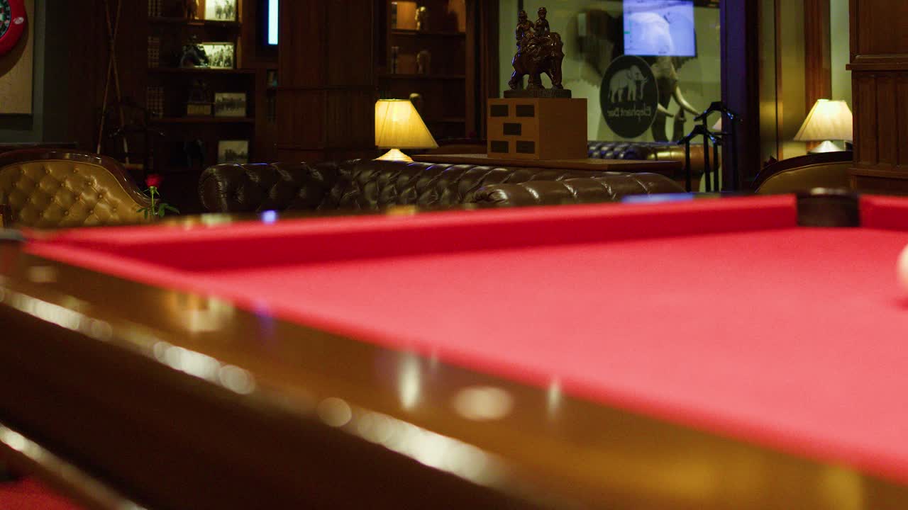 Luxurious lounge bar with leather sofas, red billiards table, warm lighting, and wood-paneled decor