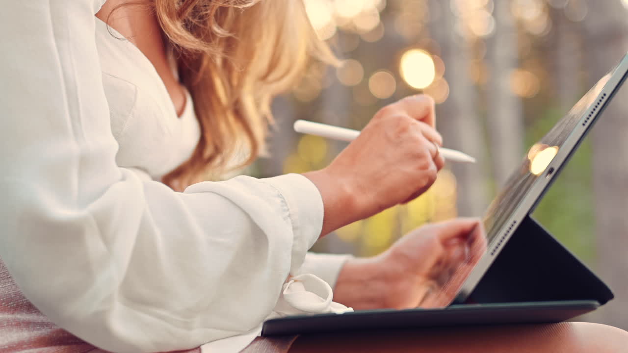 Woman sketching on a tablet with a stylus pen in the park