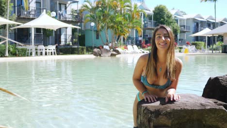 Beautiful-Lady-Leans-At-The-Big-Rock-On-The-Pool-Edge-Inside-The-Noosa-Lakes-Resort-In-Queensland,-Australia