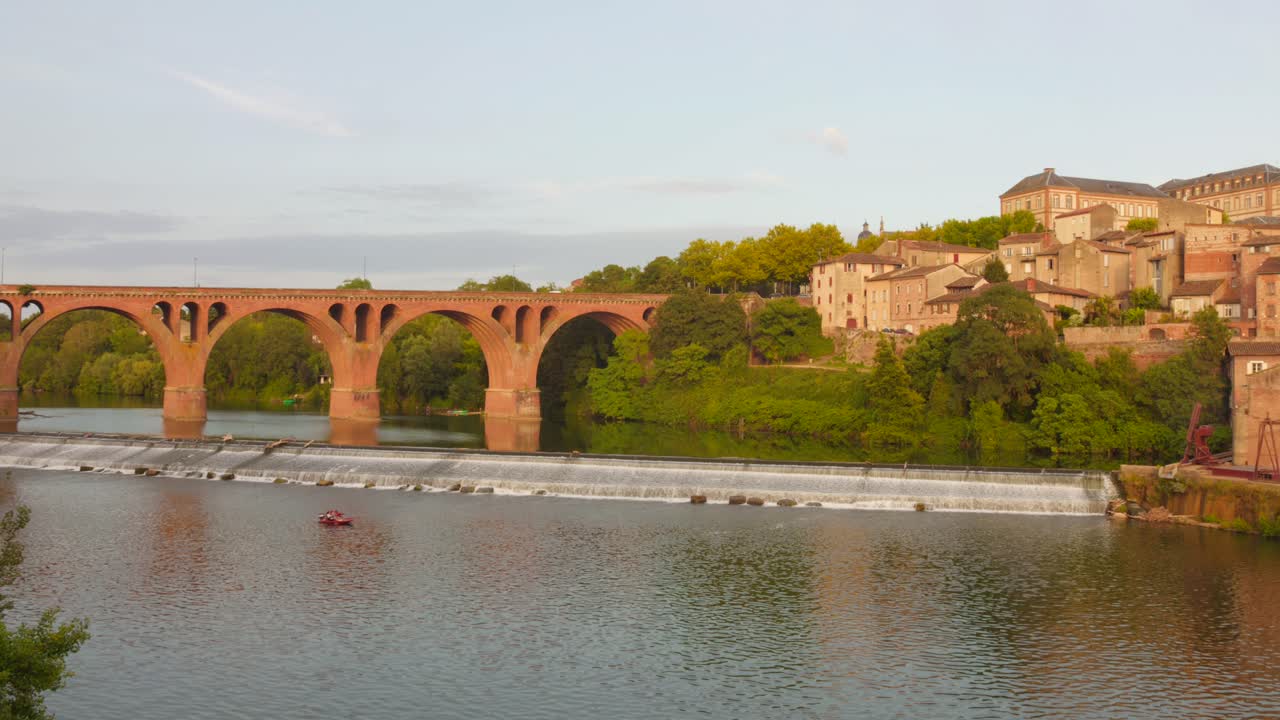 Experience breathtaking views of the Tarn River and a historic bridge in Albi, France. Captured at sunset, the scene showcases the stunning blend of architecture and nature