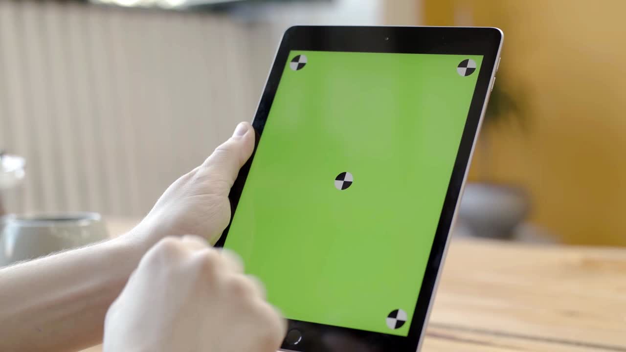 녹색 화면을 가진 태블릿을 사용하는 사람