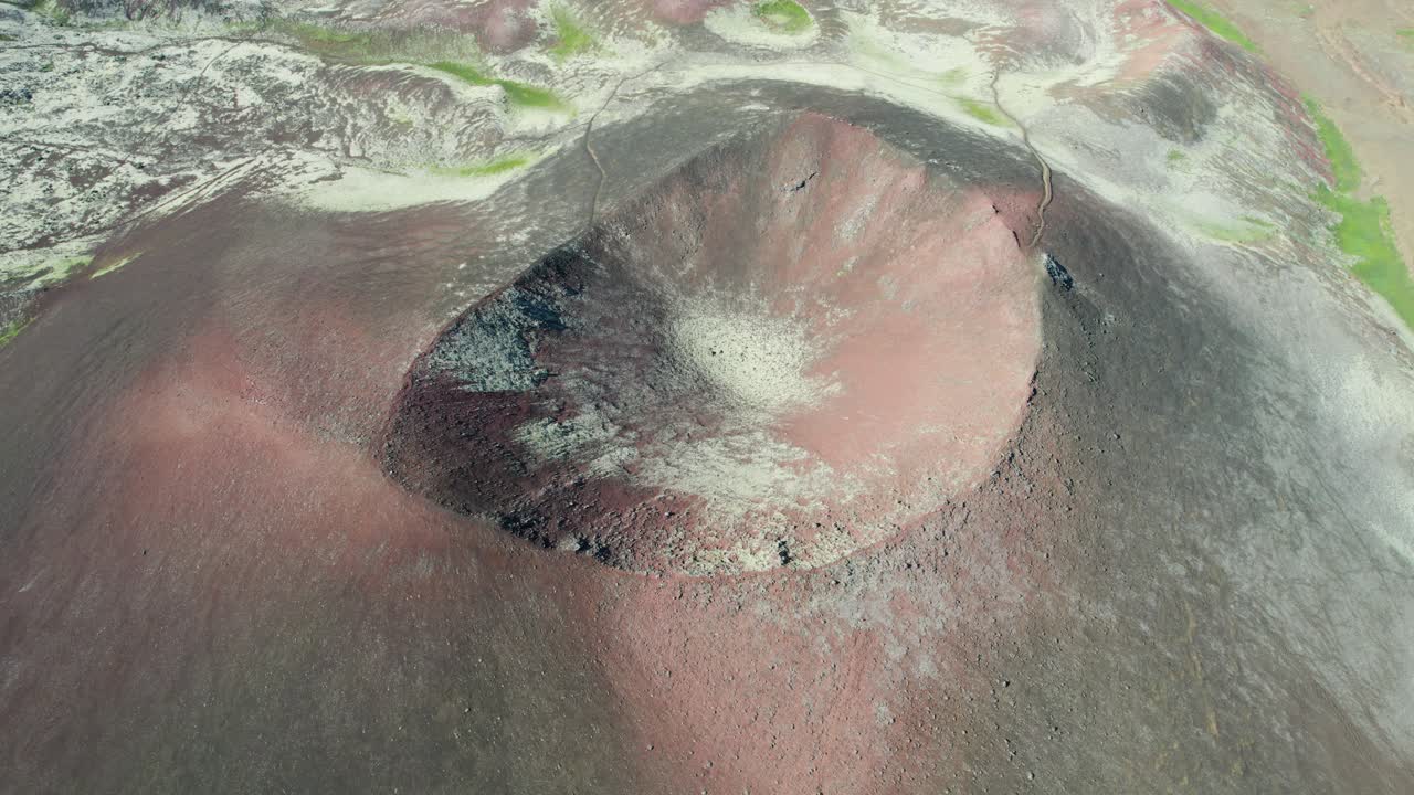 Aerial view of a volcano crater in Iceland composed of red and black rocks.
