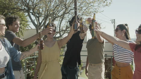 Amigos-Felices-Tintineando-Botellas-De-Cerveza-Mientras-Hacen-Una-Fiesta-En-La-Azotea