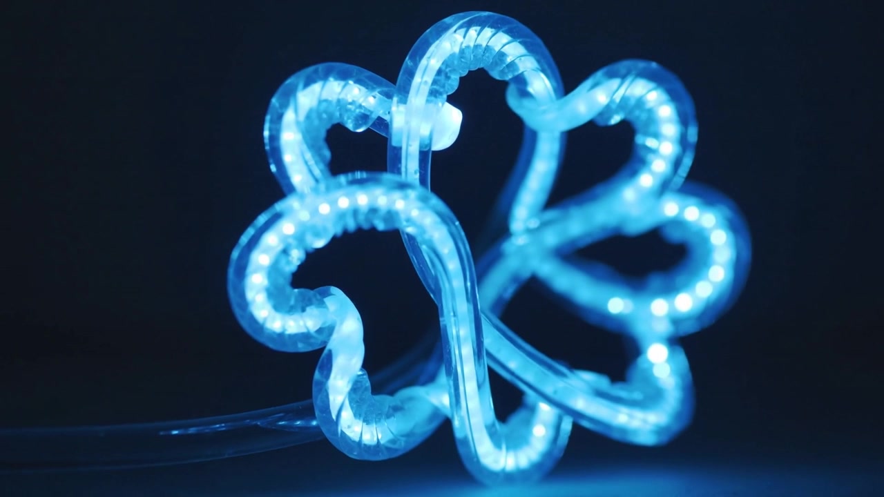 Power cable powering silicone LED rope, forming blue multi-petal flower on dark surface for display