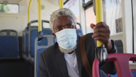 african american senior man wearing face mask travelling in the bus