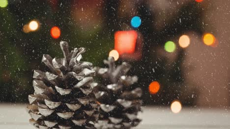 Animation-of-christmas-pine-cones,-lights-and-decorations-with-snow-falling
