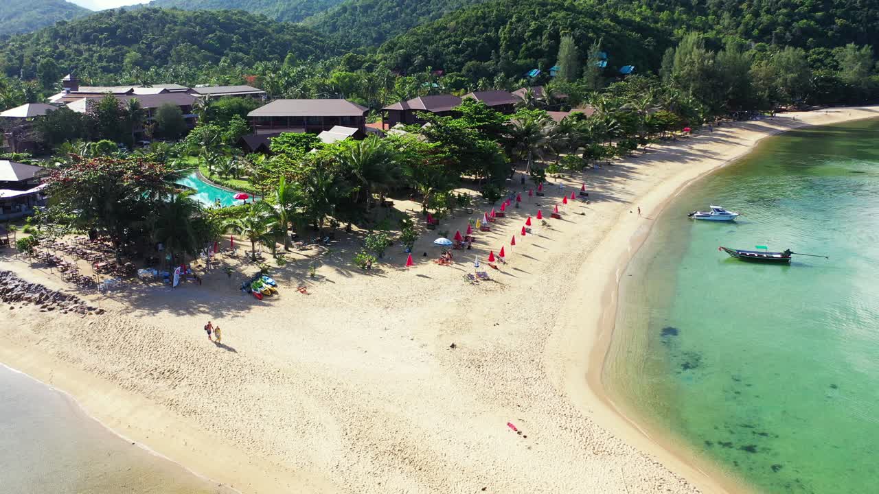 White sand of exotic beach with sunbeds and umbrellas near vacations resort on tropical island washed by turquoise lagoon in Thailand