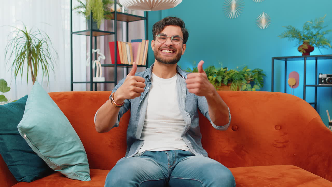 joven indio feliz mirando con aprobación a la cámara muestra los pulgares hacia arriba como un signo positivo buenas noticias
