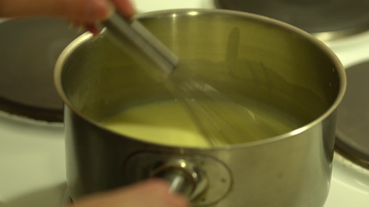 Stirring creamy sauce in a small pan with the metallic whisk, STILL