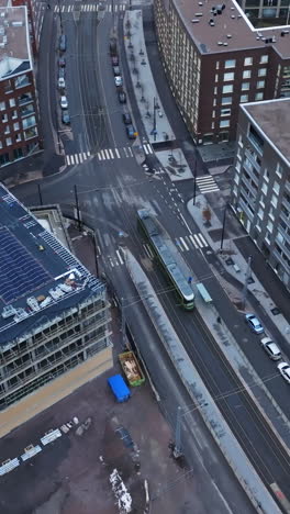 vertical drone shot following a lightrail on the streets of helsinki, cloudy day